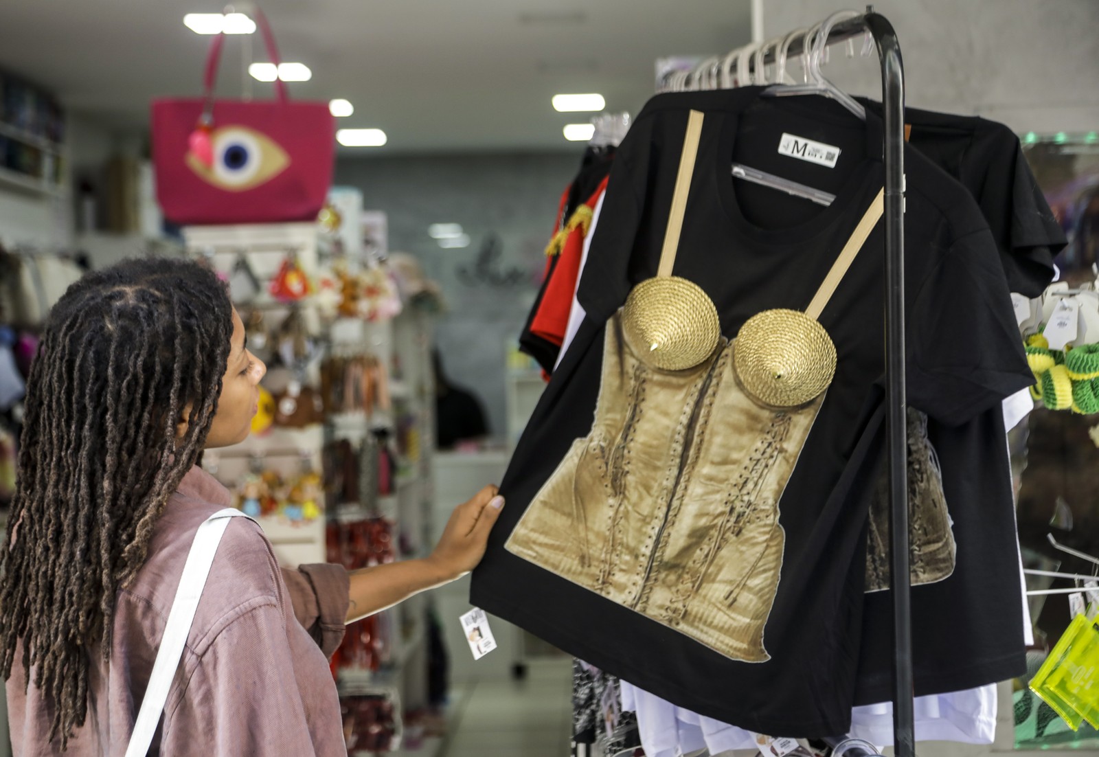Loja da Saara vende produtos para o show da Madonna e tem grande procura. Maiara Andrade de Lima adorou a camisa com peitos. — Foto: Gabriel de Paiva