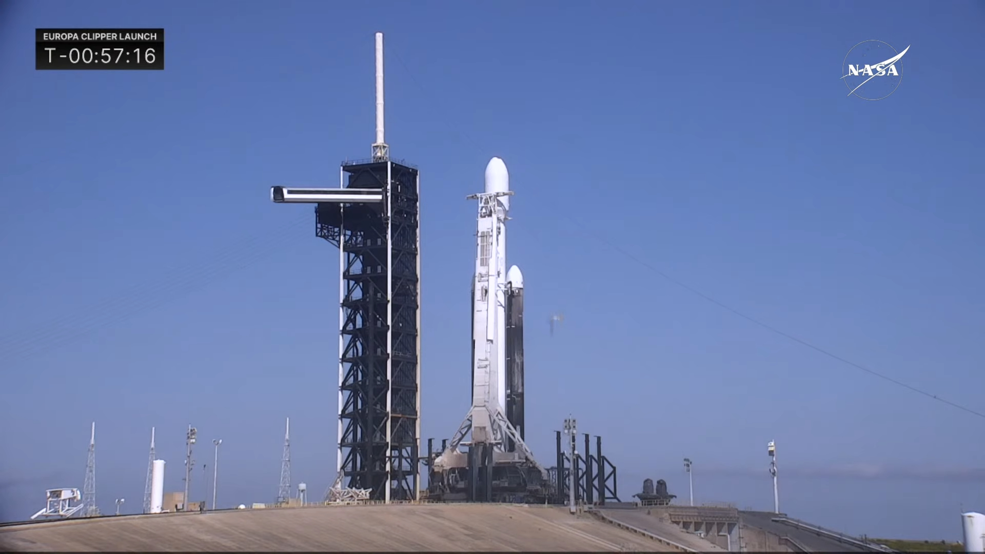 A SpaceX Falcon Heavy rocket on the launch pad at dawn with its reflection in the bay nearby